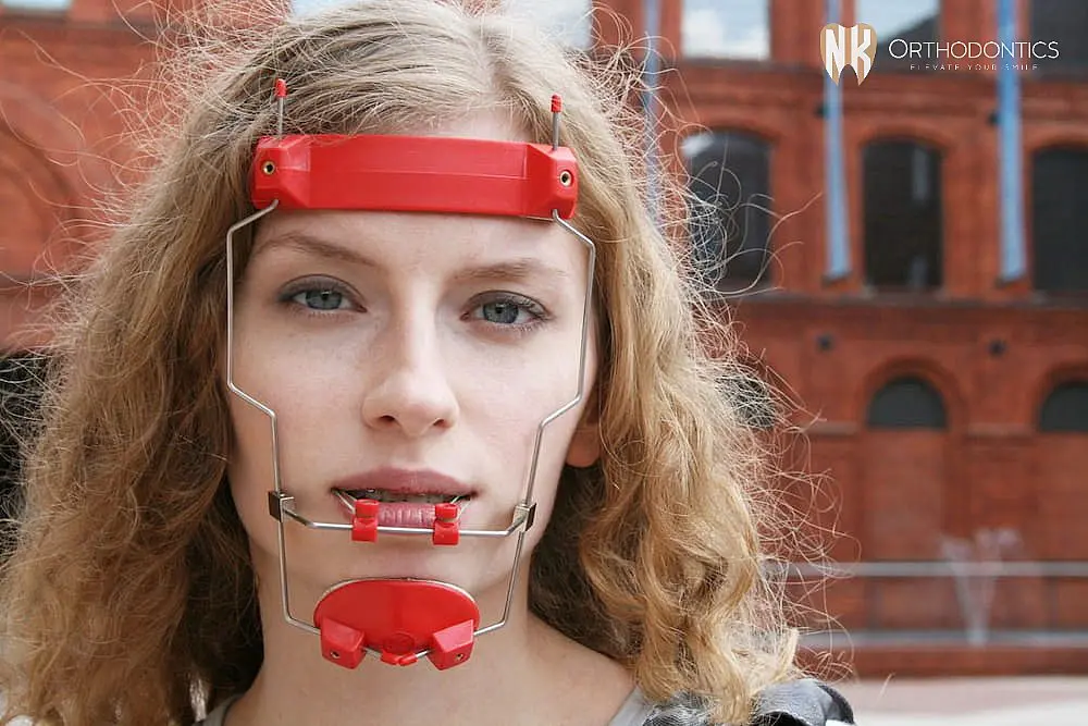 A person with curly hair dons orthodontic headgear from NK Orthodontics, set against a backdrop of red brick buildings in Suwanee or Tucker, GA