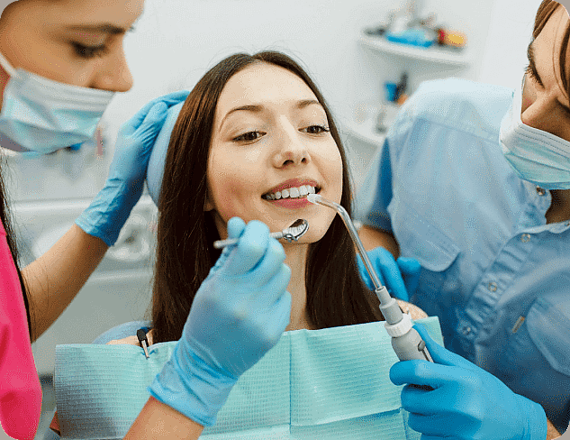 Dentist and assistant expertly perform a dental procedure on a smiling female patient in the clinic, highlighting the effectiveness of adult orthodontics in enhancing her confident grin in Suwanee or Tucker, GA