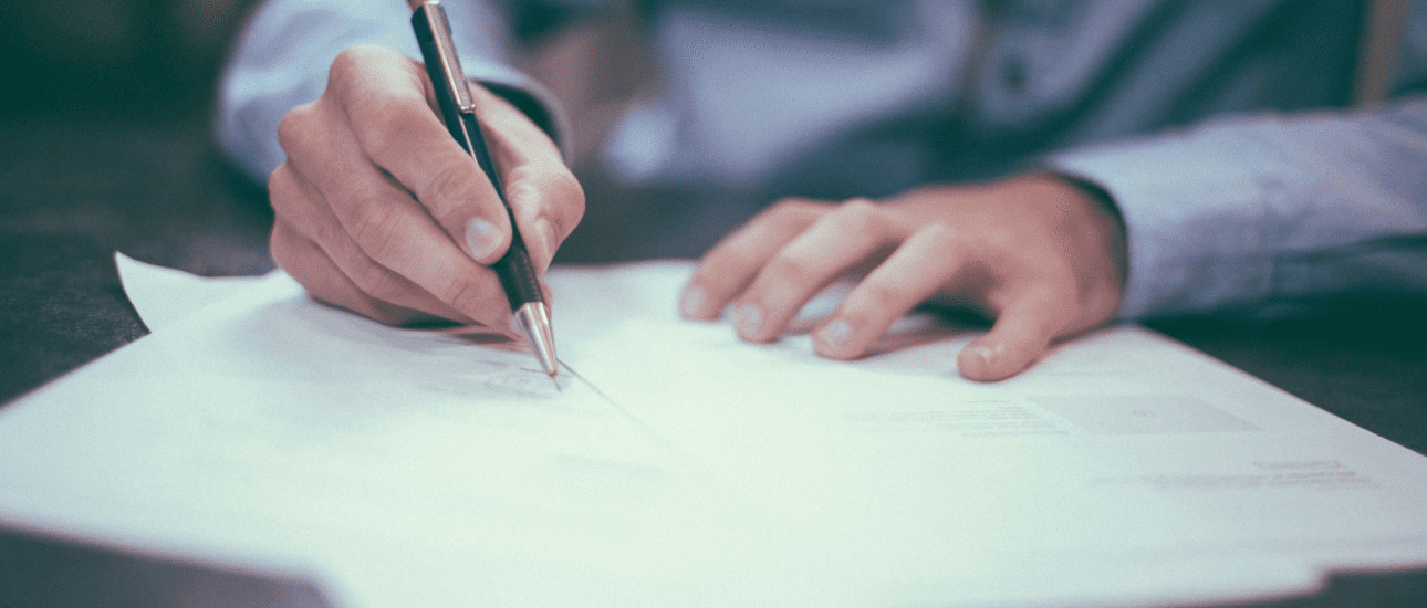 A person in a blue shirt is meticulously writing on a stack of papers at the table, likely reviewing orthodontic insurance documents with focused attention in Suwanee or Tucker, GA