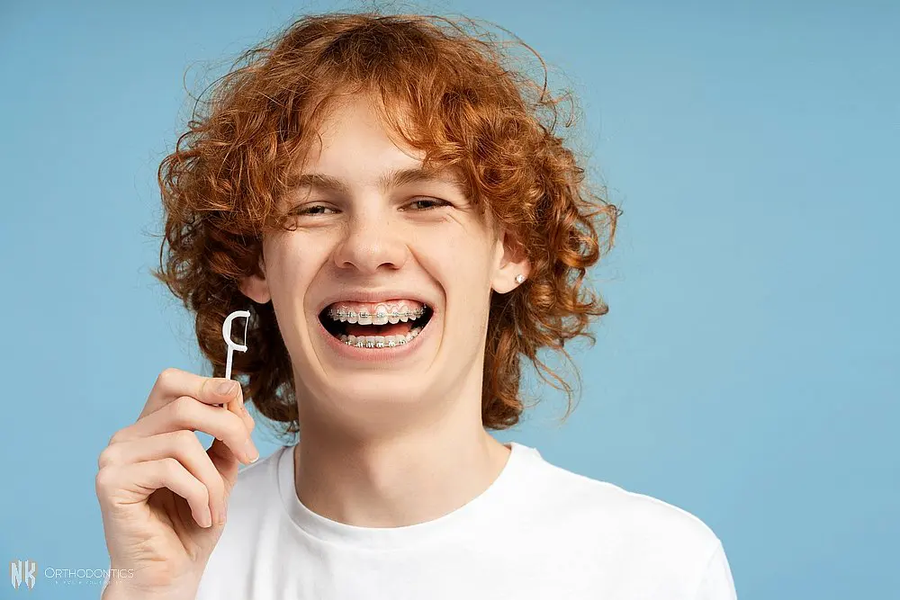closeup image smiling teenager curly red hair metal braces - How to Floss with Braces in Suwanee and Tucker, GA. 