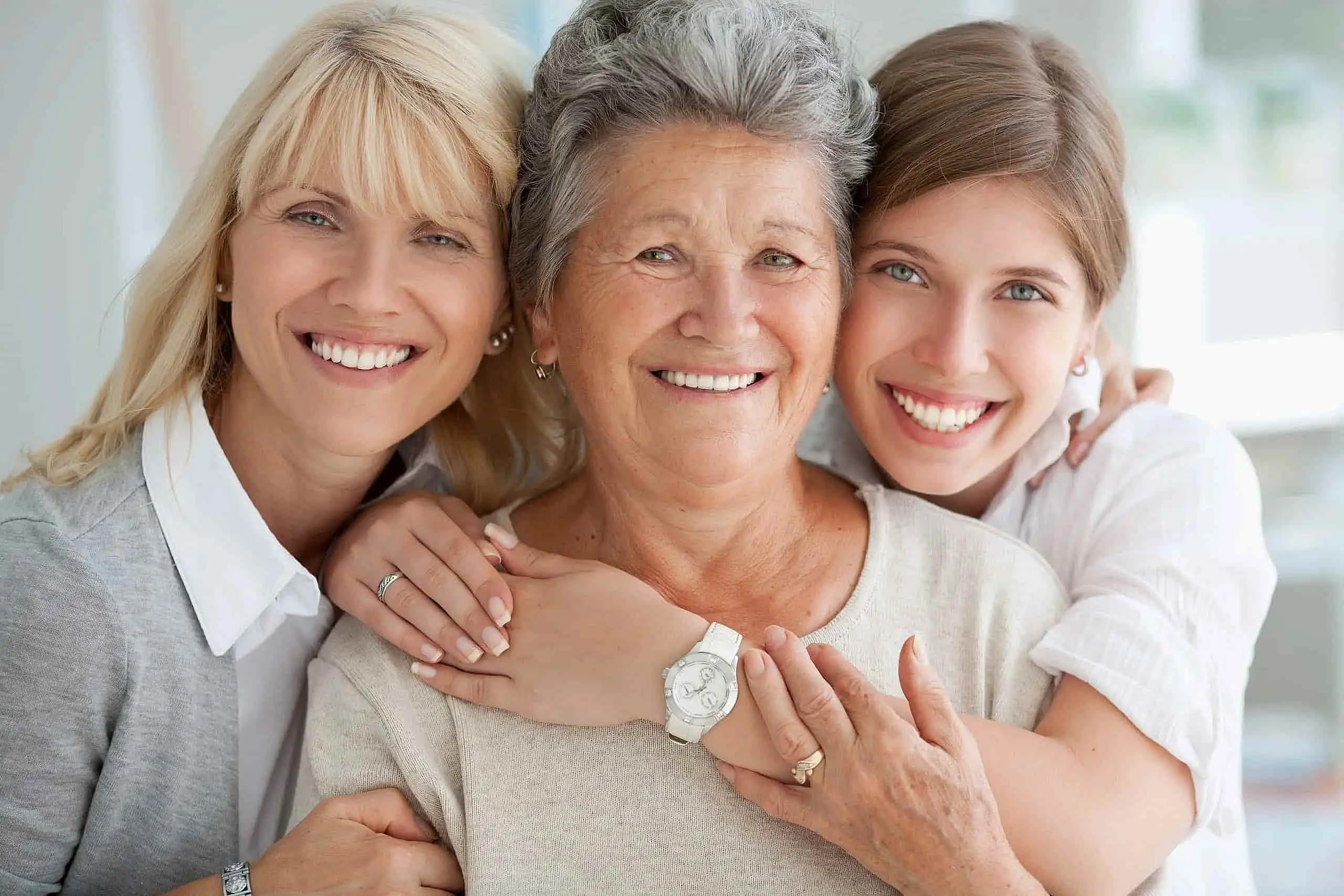 Three women of different ages smiling and posing closely together, highlighting the best adult orthodontic treatment options at NK Orthodontics in Suwanee or Tucker, GA.