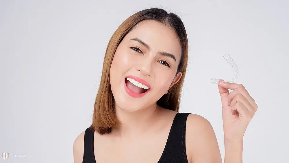young smiling woman holding invisalign clear aligners studio dental health care orthodontic - How Long Does Invisalign Take in Suwanee and Tucker, GA 