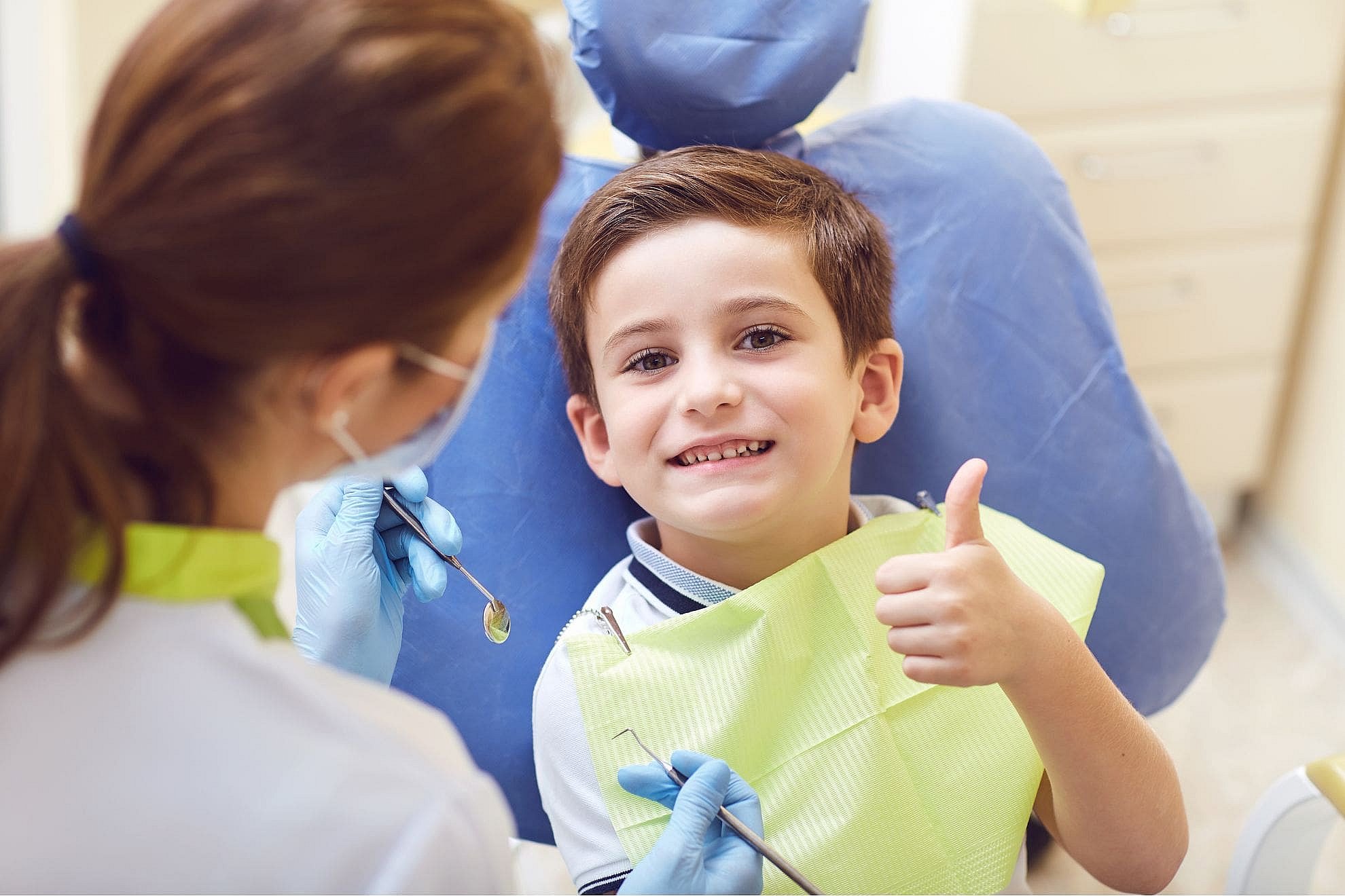 A children's orthodontist discusses with a child about the importance of Early Evaluation for dental care in a chair in the clinic in Suwanee or Tucker, GA.